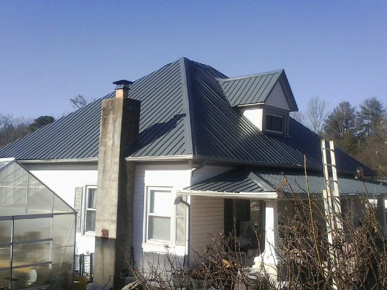 Dark blue standing seam metal roof on a white farmhouse with dormer — Slate & Tile Roof Repair by Roofing Brothers in Pompton Lakes