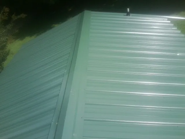 New green metal panels meeting at the ridge of a roof — Flat Roof Repair work by our crew in Pompton Lakes