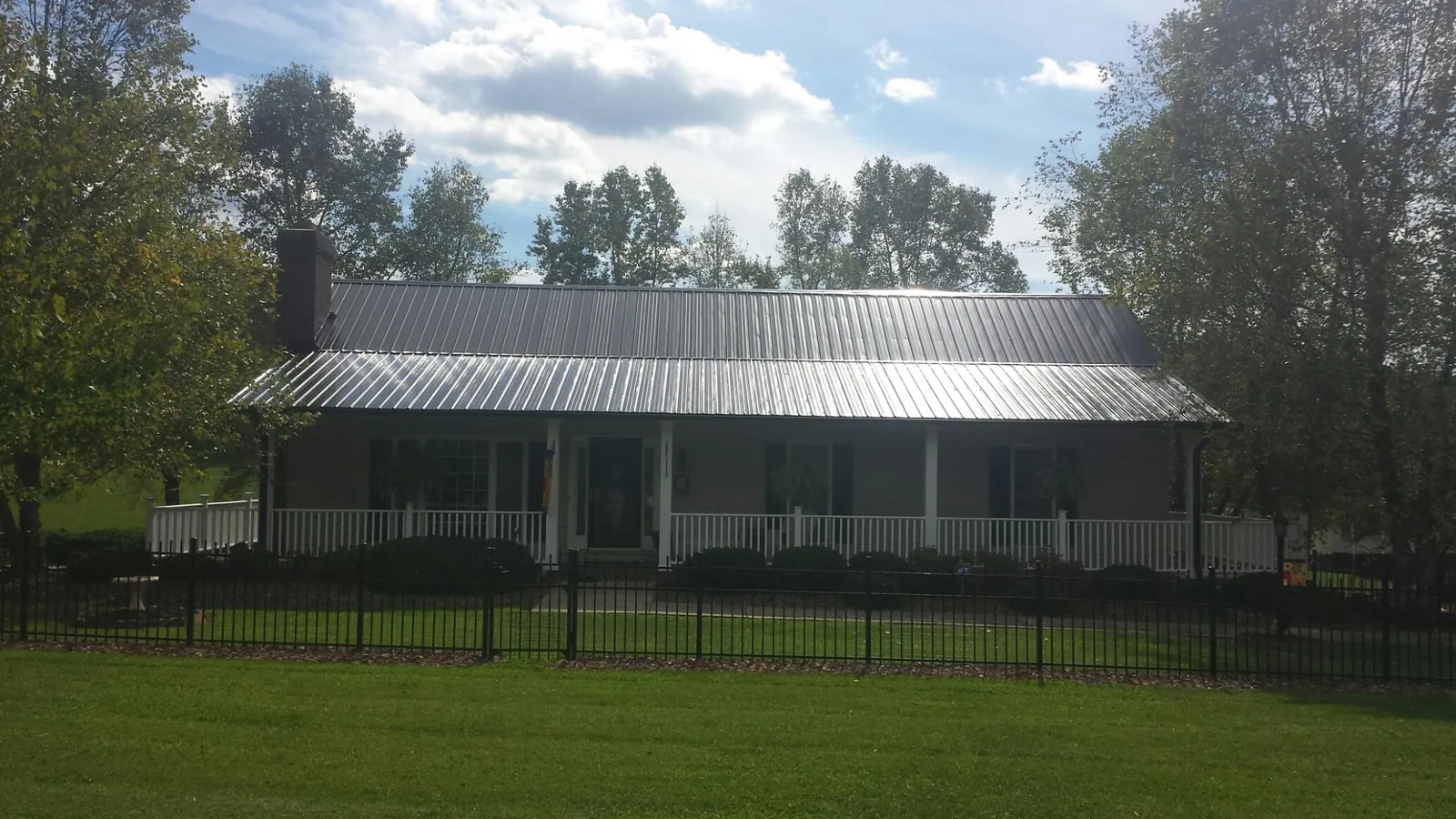 Gray metal roof on a brick ranch with a full width front porch — Gutter Guard Installation work by our crew in Pompton Lakes