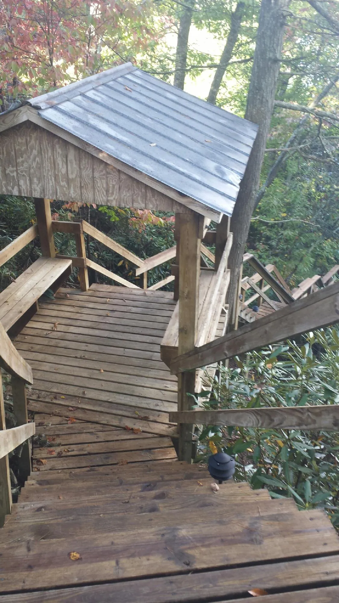 Metal roofed shelter over wooden steps on a wooded walkway — Skylight Repair & Installation work by our crew in Pompton Lakes