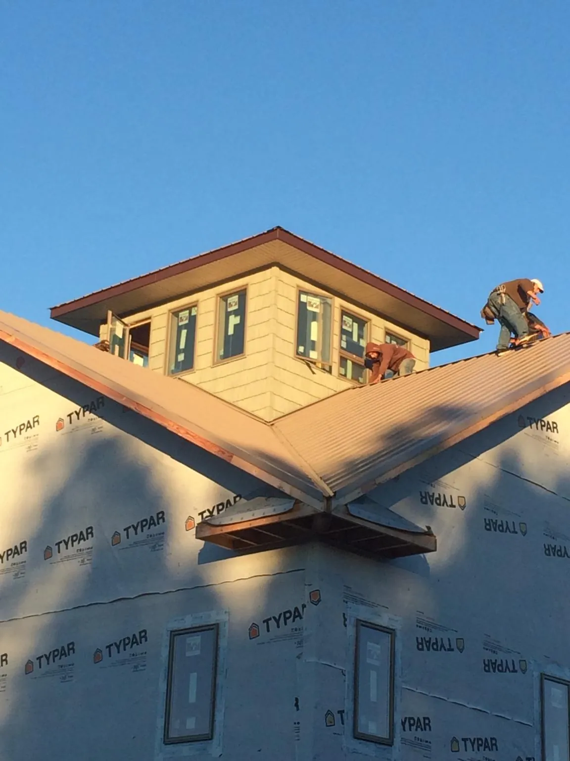 Roofers working around a rooftop cupola on a new metal roof at sunset — Roof Waterproofing in Pompton Lakes by Roofing Brothers